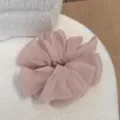Vue détaillée de la pince à cheveux en résille rose, avec texture de fleur en mousseline. - Rose Doux