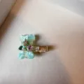 Primo piano della graziosa molletta per capelli orso in acetato verde con strass brillanti. - Blu