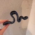 Primo piano di un fermaglio per capelli a serpente in strass nero con dettagli unici. - blu stellato