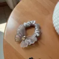 Vista dettagliata di un elastico per capelli con farfalla in rete di strass, elegante. - Champagne