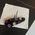 Dettaglio del fermaglio per capelli con fiori in strass, elegante molletta nera in tessuto luminoso. - Color block viola scuro