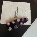 Dettaglio del fermaglio per capelli con fiori di strass e cristalli su tessuto nero. - Blocco Colore Strass Rosa