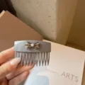 Dettaglio ravvicinato del pettine per capelli in acrilico grigio con fiocco in perle e strass. - Grigio高级
