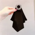 Vista detallada de un elegante lazo negro con un muy brillante broche de pedrería fina. - Estilo Principal