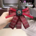 Gros plan détaillé d'une élégante broche nœud écossais rouge avec centre de fleurs en strass. - Rouge