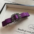 Dettaglio fermaglio per capelli fiocco in raso viola con strass brillanti, elegante. - Viola
