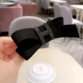 Ferma capelli nero con fiocco in tessuto e fibbia H di strass elegante accessorio da donna. - Nero