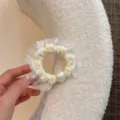 Inquadratura dettagliata di elegante scrunchie in pizzo bianco con perla e tessuto morbido. - Giallo Formaggio