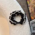 Detail shot of a black and white mesh ruffled hair scrunchie, showing delicate texture and design. - Oval Bead / Black