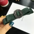 Primo piano dettagliato della molletta per capelli con fiocco in velluto verde scuro e strass. - Verde