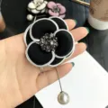 Elegante spilla a forma di camelia in tessuto nero con strass brillanti per donna. - Nero