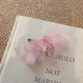 Primo piano di un grazioso fermaglio per capelli con fiocco in rete rosa, stile fatato. - rosa pesca