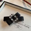 Primo piano dettagliato della molletta per capelli con fiocco in raso nero e strass. - Nero