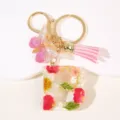 Detailweergave van de hars gedroogde bloem letter sleutelhanger met roze kwastje. - Letter B
