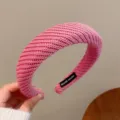 Vista detallada de una elegante diadema rosa de punto con etiqueta artesanal, textura suave. - Rosa