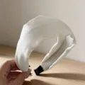 Vista detallada de una diadema ancha de raso blanco, elegante accesorio para el pelo. - Blanco Roto
