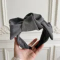 Primo piano dettagliato del cerchietto in tessuto grigio scuro con fiocco vintage. - FK-B974 Grigio