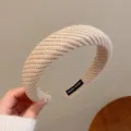 Gros plan du serre-tête tricoté beige, bandeau souple tressé avec étiquette artisanale chic. - Kaki