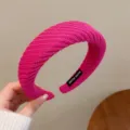 Gros plan détaillé d'un serre-tête large en tricot rose vif avec étiquette fait main. - Rose rouge