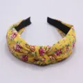 Primer plano detallado de la diadema de tela amarilla con estampado floral y nudo. - Amarillo