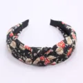 Primer plano detallado de la diadema de tela negra con estampado floral y nudo elegante. - Negro