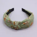 Green floral fabric headband with stylish knotted design for women, elegant hair accessory detail. - Green