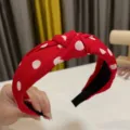 Vista detallada de diadema roja con lunares blancos y nudo, mostrando la textura y el diseño. - Rojo