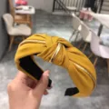 Primer plano de la diadema de tela amarilla con un elegante nudo dorado trenzado. - Amarillo