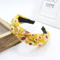 Vista detallada de una diadema con nudo floral amarillo y estampado de margaritas, elegante. - Amarillo