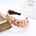 Detailed close-up of a pink floral knotted fabric headband with vintage daisy print design. - Pink