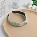 Primer plano de la suave diadema de tela floral con nudo, con detalles y patrones exquisitos. - Verde