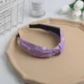 Vista detallada de una diadema con nudo floral morado, exhibición de escritorio estética con accesorios. - Púrpura