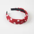 Primer plano detallado de la elegante diadema de tela roja con lunares blancos y nudo. - Burdeos