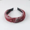Detalle en primer plano de diadema de tela con estampado paisley rojo y elegante nudo. - Burdeos