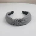 Detalle en primer plano de la diadema de tela gris con nudo, accesorio minimalista. - Gris