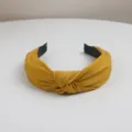 Close-up view of a mustard yellow fabric knotted hairband showing textured fabric details. - Yellow