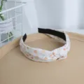 Primer plano detallado de la diadema de tela con nudo y un bonito estampado floral. - Naranja