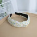 Vista detallada de una diadema de tela floral con un bonito diseño de nudo frontal. - Amarillo