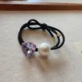 Primo piano dettagliato di un elegante elastico per capelli nero con cristallo viola. - Viola