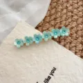 Dettaglio in primo piano del grazioso fermaglio per capelli floreale con strass azzurro. - Fermaglio Laterale / Fiore Strass Blu-Verde