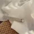 Primo piano dettagliato del fermaglio per capelli con strass splendenti per un look elegante. - Strass Bianco