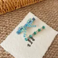 Close-up detail showing a cute colorful striped bow hair clip and green rhinestone barrette. - Blue-Green Crystal Bow Set