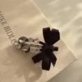 Detailed shot of black bow hair clip with sparkling rhinestones on canvas background. - Black