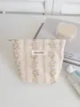 Detail view of the floral cosmetic bag, featuring elegant vintage jacquard fabric and brand label. - S / Striped Rose