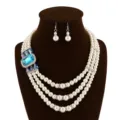 Detailopname van de meerlaagse parelketting met een groot blauw kristal en bijpassende oorbellen. - Meerblauw