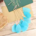Detail van bohemian veer kwast oorclip met levendige blauwe veren en delicate gouden kettingen. - Meerblauw