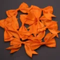 Close-up detail of vibrant orange satin swallowtail ribbon bows, perfect for gift packaging and DIY crafts. - 2.5cm Width (10 Pieces/Pack) / Orange