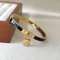 Goldfarbenes Edelstahl Armband mit schwarzer Emaileinlage und graviertem Vorhängeschloss. - Schwarz