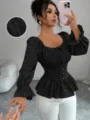 Primer plano detallado del top negro texturizado de manga larga con elegantes motivos florales. - S / Tops / Negro