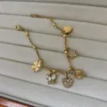Gouden roestvrijstalen bedelarmband met zircone klaverblad en vlinderaccenten. - Hart en Ster Stijl / Goud